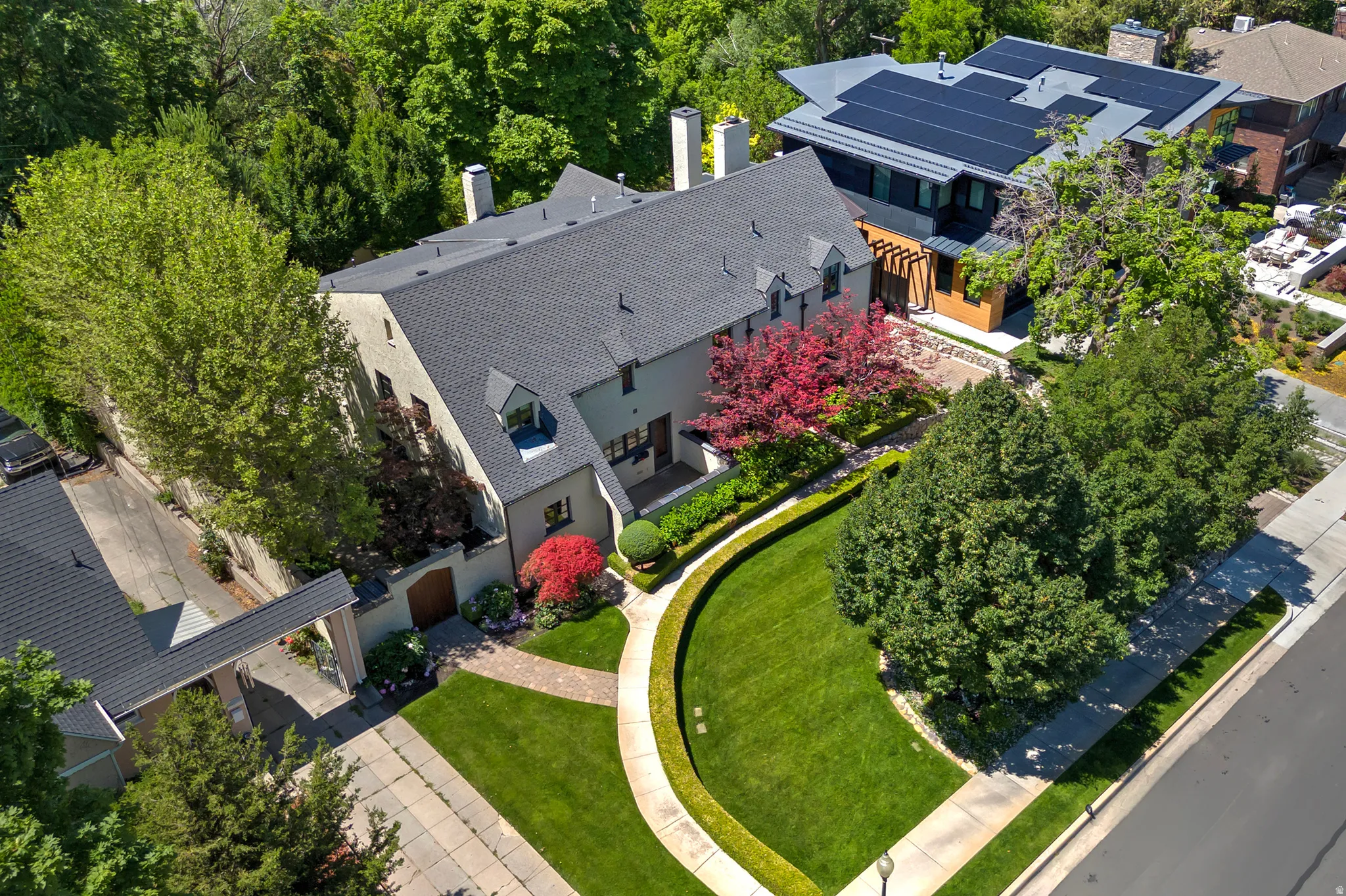 Stucco exterior featuring a dark shingle roof, multiple chimneys, and architectural dormer windows