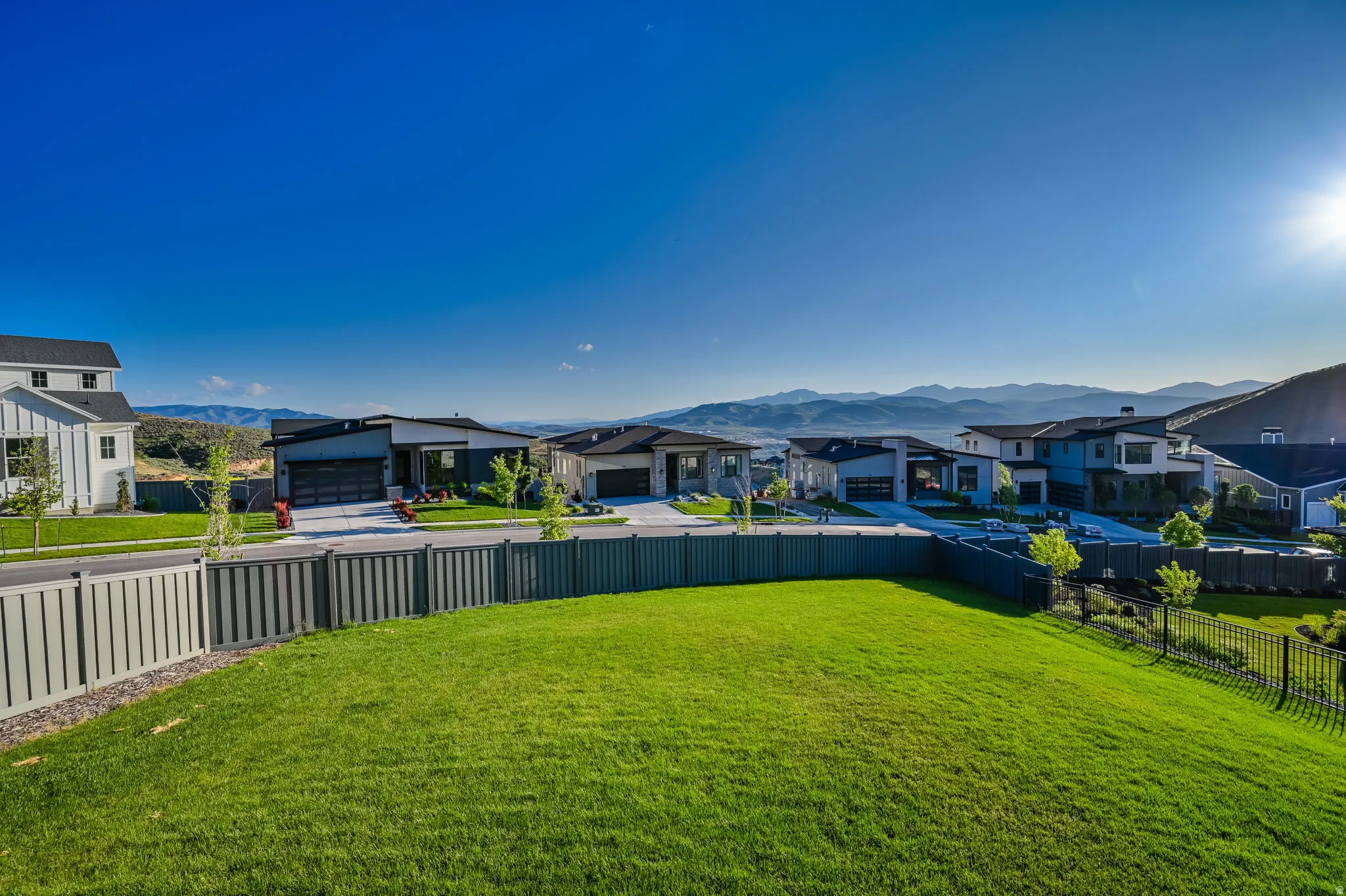 Expansive green lawn bounded by a privacy fence and black metal fencing