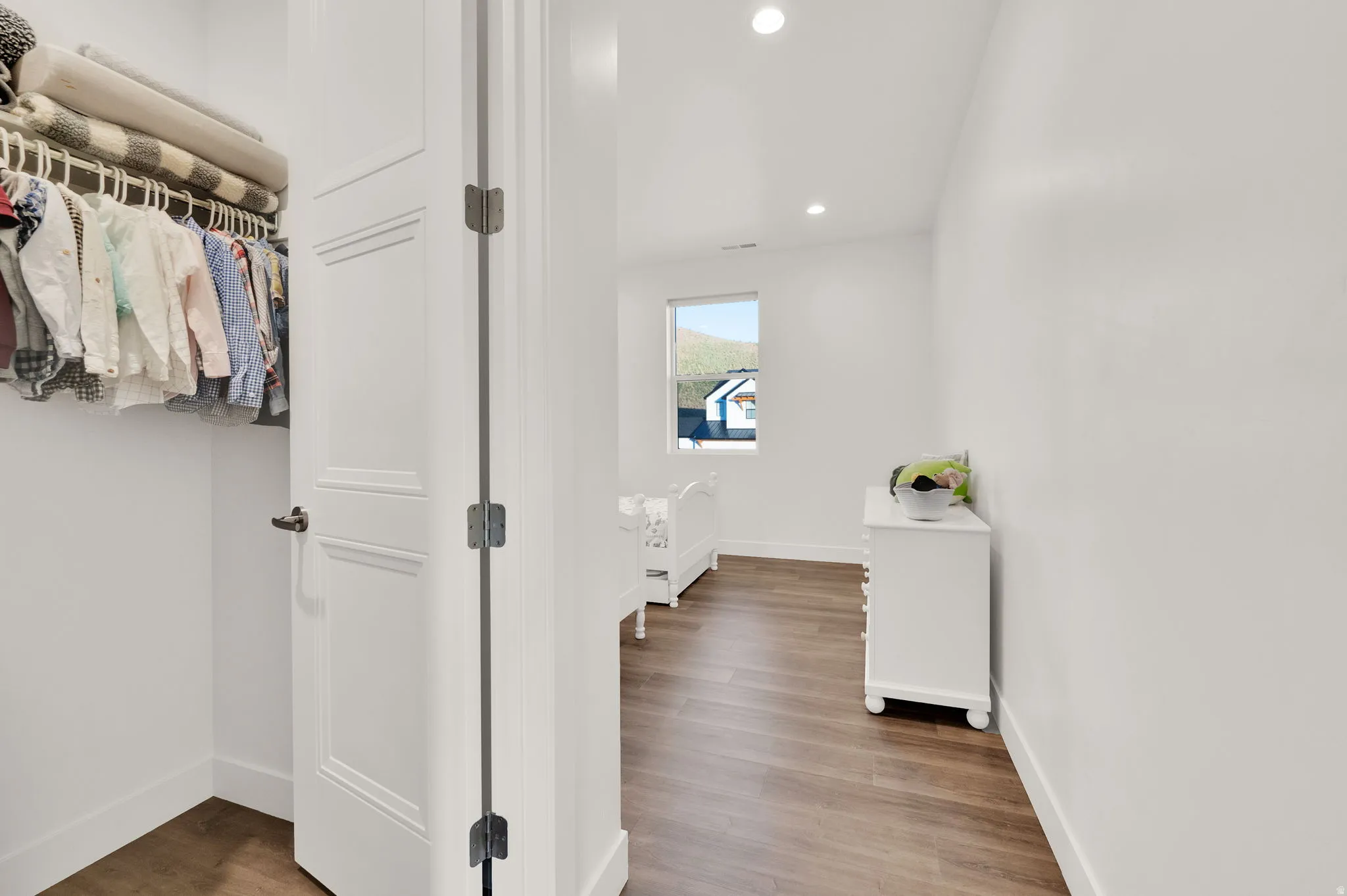 Bright white walls with recessed lighting and wood-finish flooring characterize this room