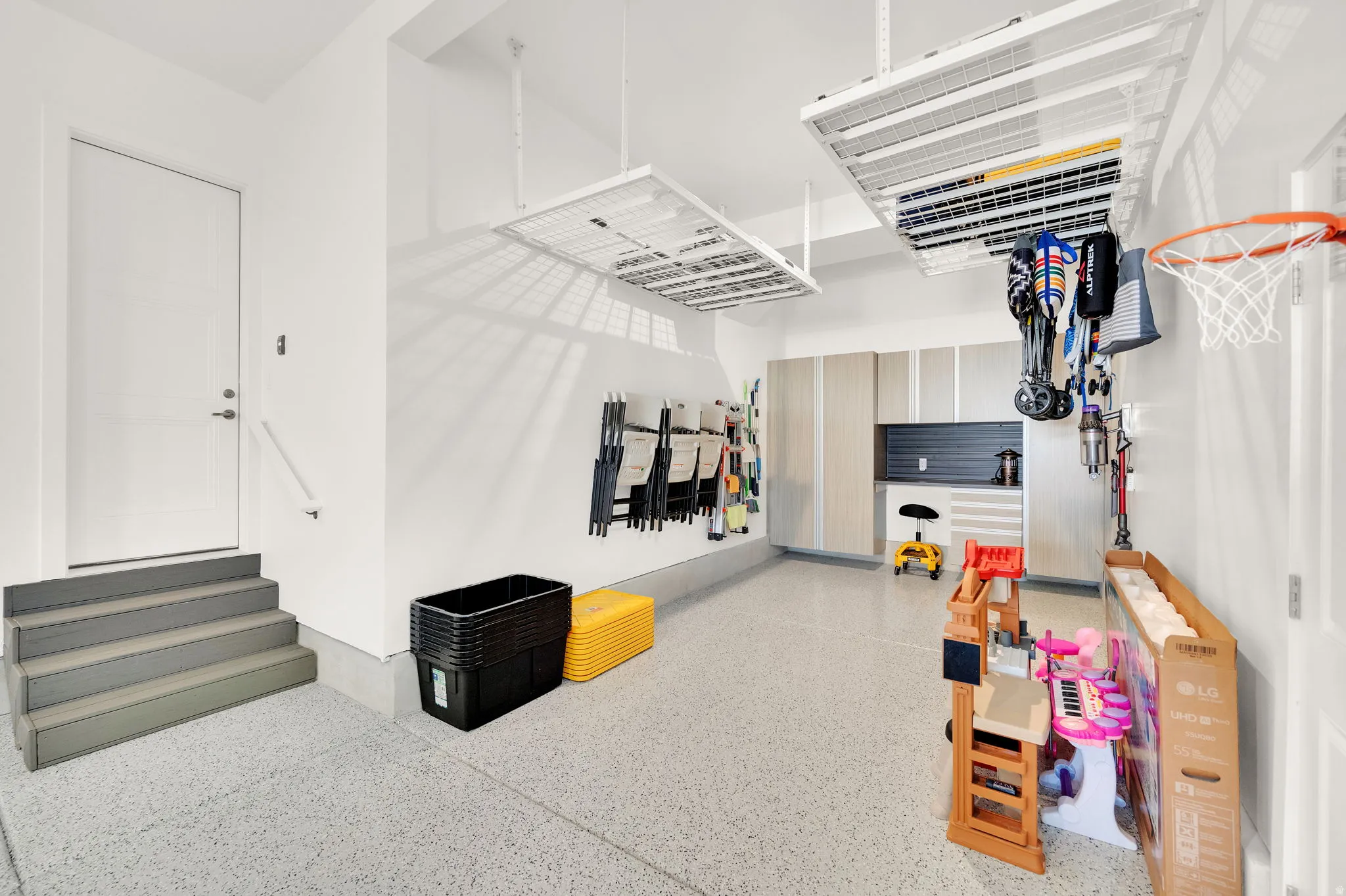 Spacious garage featuring a durable epoxy floor, integrated overhead storage racks, a dedicated storage system with cabinetry and slatwall, and an internal access door