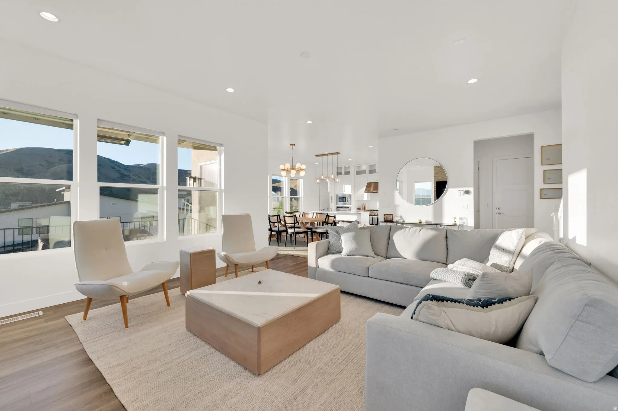 Open-concept living space with white walls and wood-finish flooring