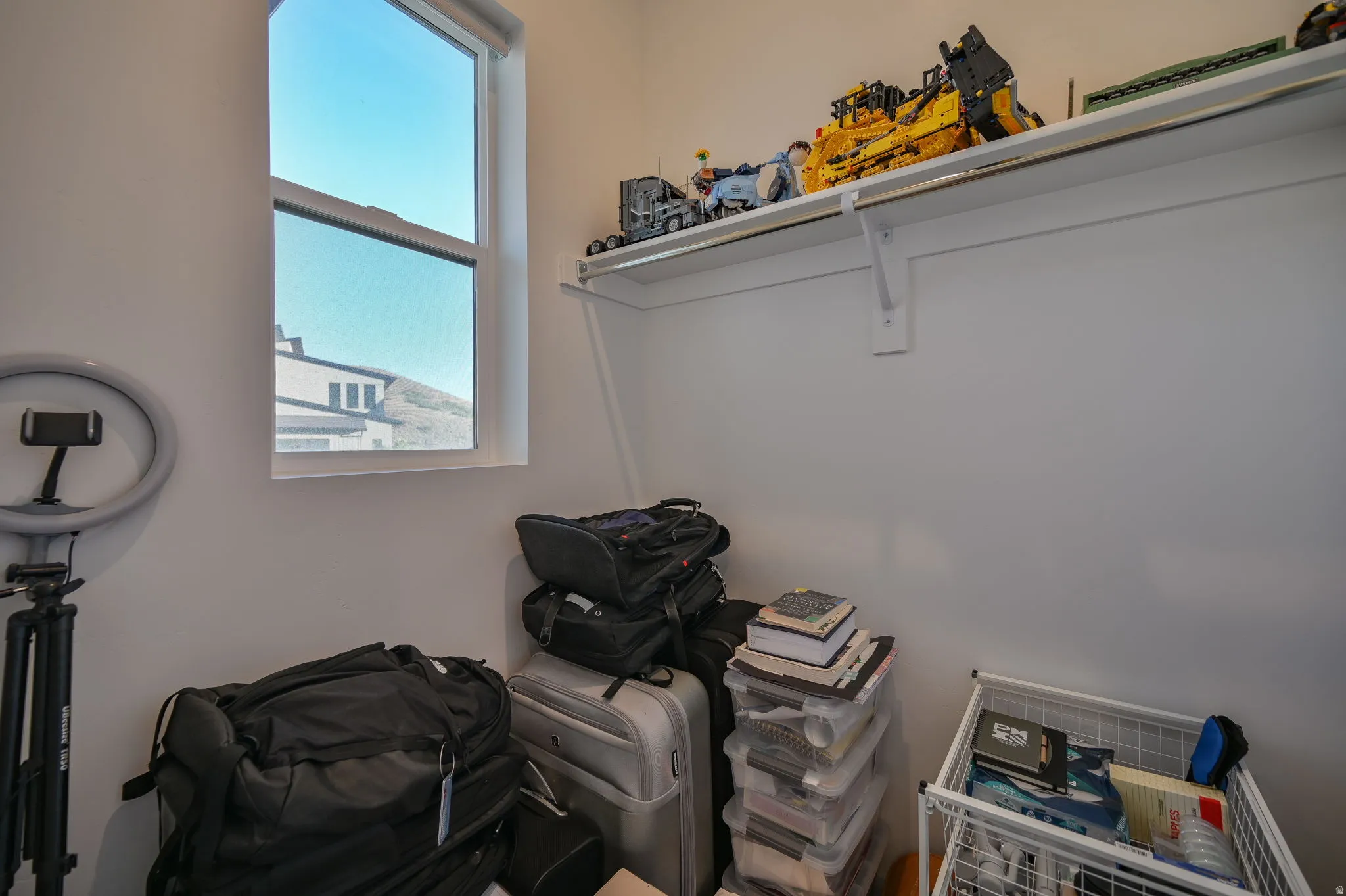 White painted walls with a single casement window, featuring a built-in shelf and clothing rod