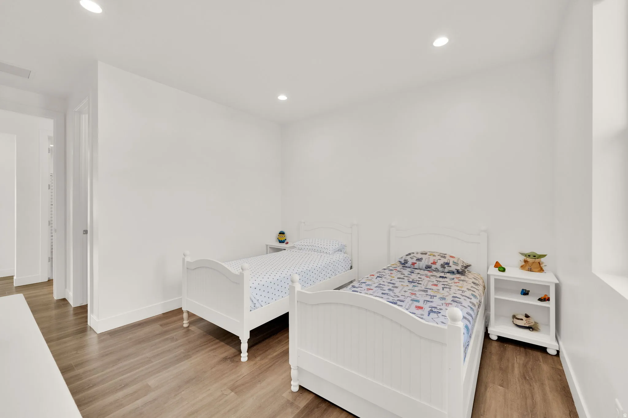 Bright room featuring wood-finish flooring, recessed lighting, white walls, and a window providing natural light