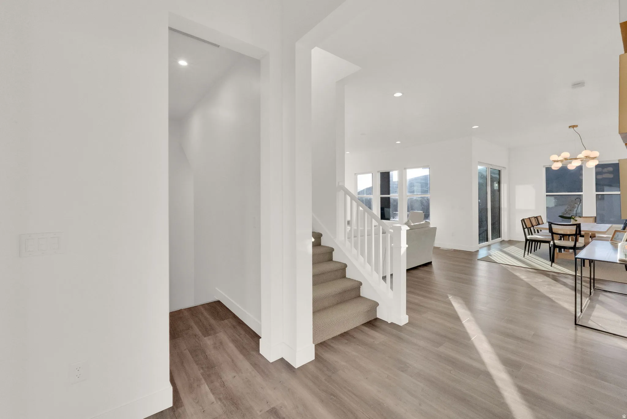 Open concept living space featuring wood-finish flooring, white walls, and recessed lighting