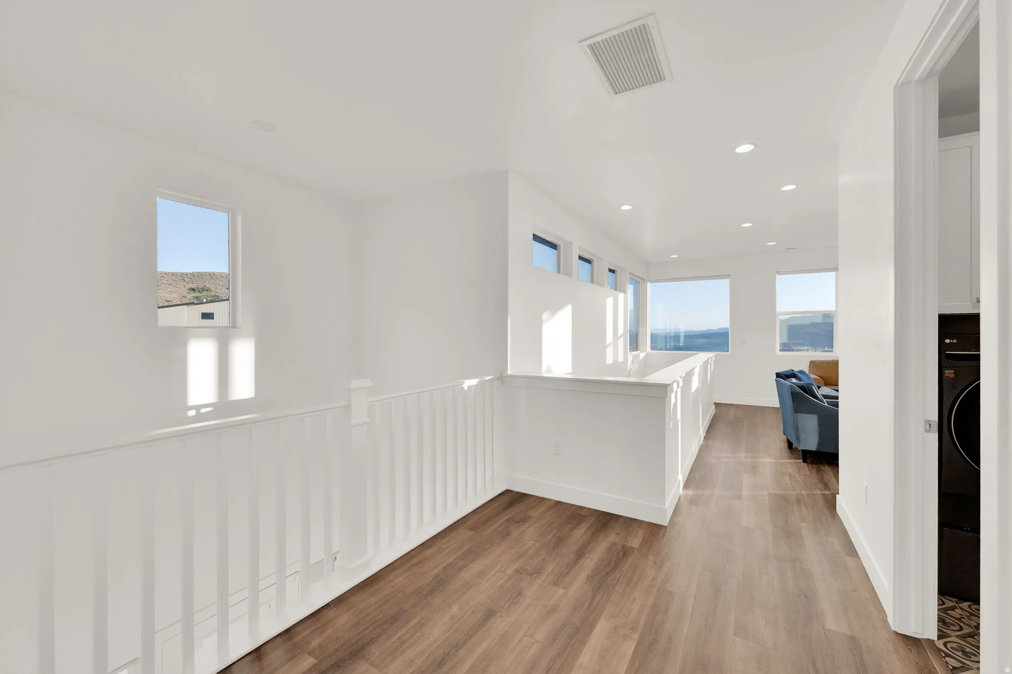 Hallway featuring wood-finish flooring, white walls, and recessed lighting