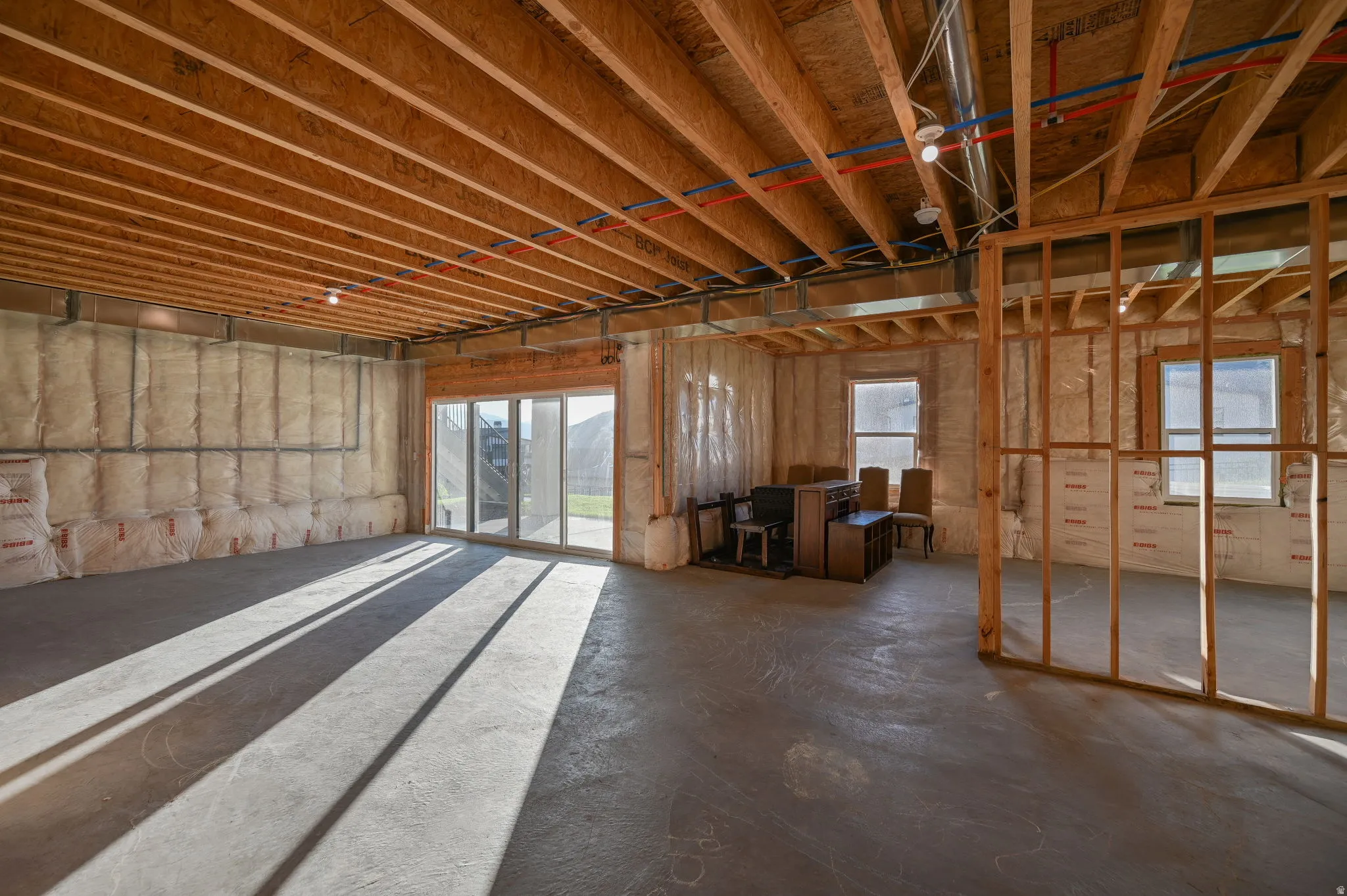 Unfinished lower level with exposed ceiling joists and concrete flooring