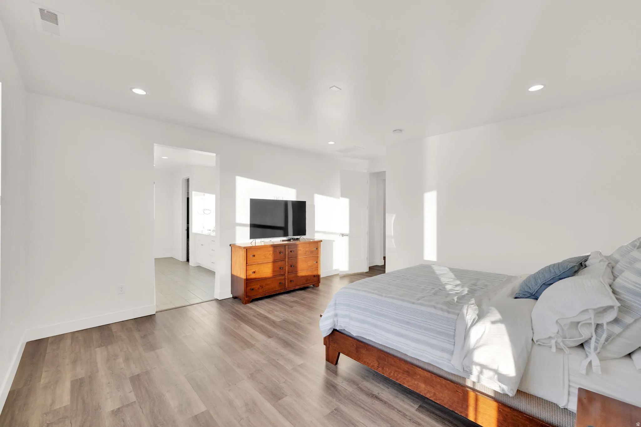 Spacious room featuring wood-finish flooring, recessed lighting, and bright white walls