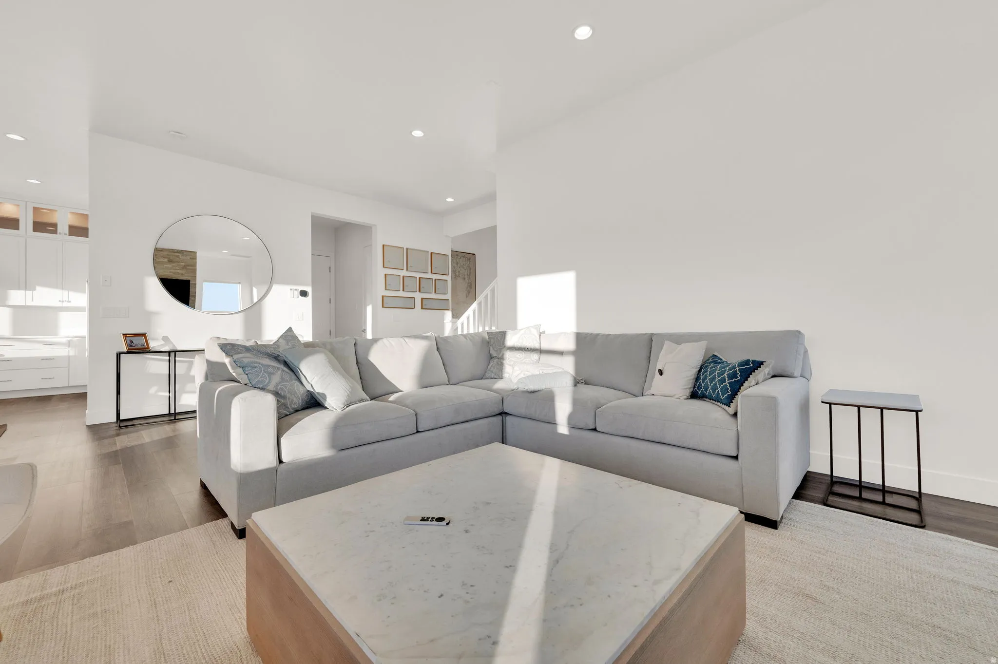 Open-concept living area featuring wood-finish flooring, recessed lighting, and crisp white walls