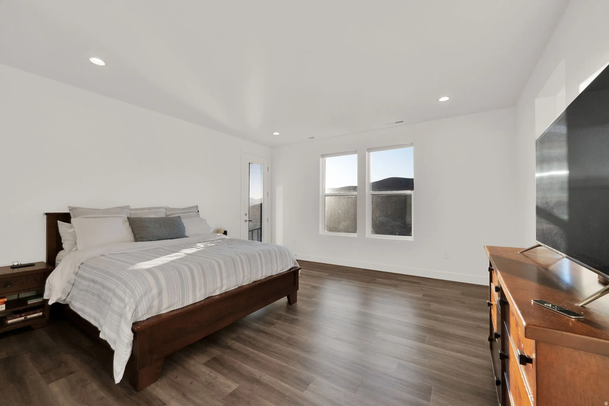Spacious room featuring wood-finish flooring, recessed lighting, and white walls