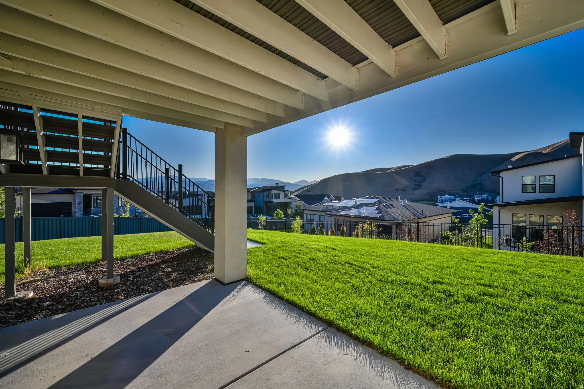 Covered patio with concrete flooring, extending to a manicured lawn