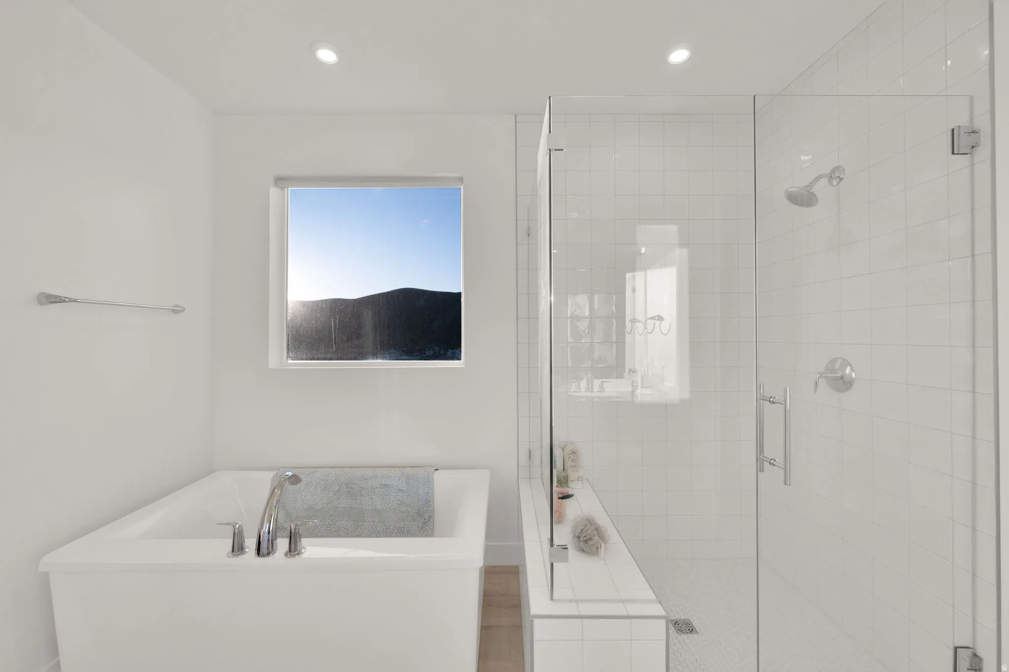 Modern bathroom featuring a built-in soaking tub with chrome fixtures, a glass-enclosed shower with subway tile surround, recessed lighting, and a window with natural light