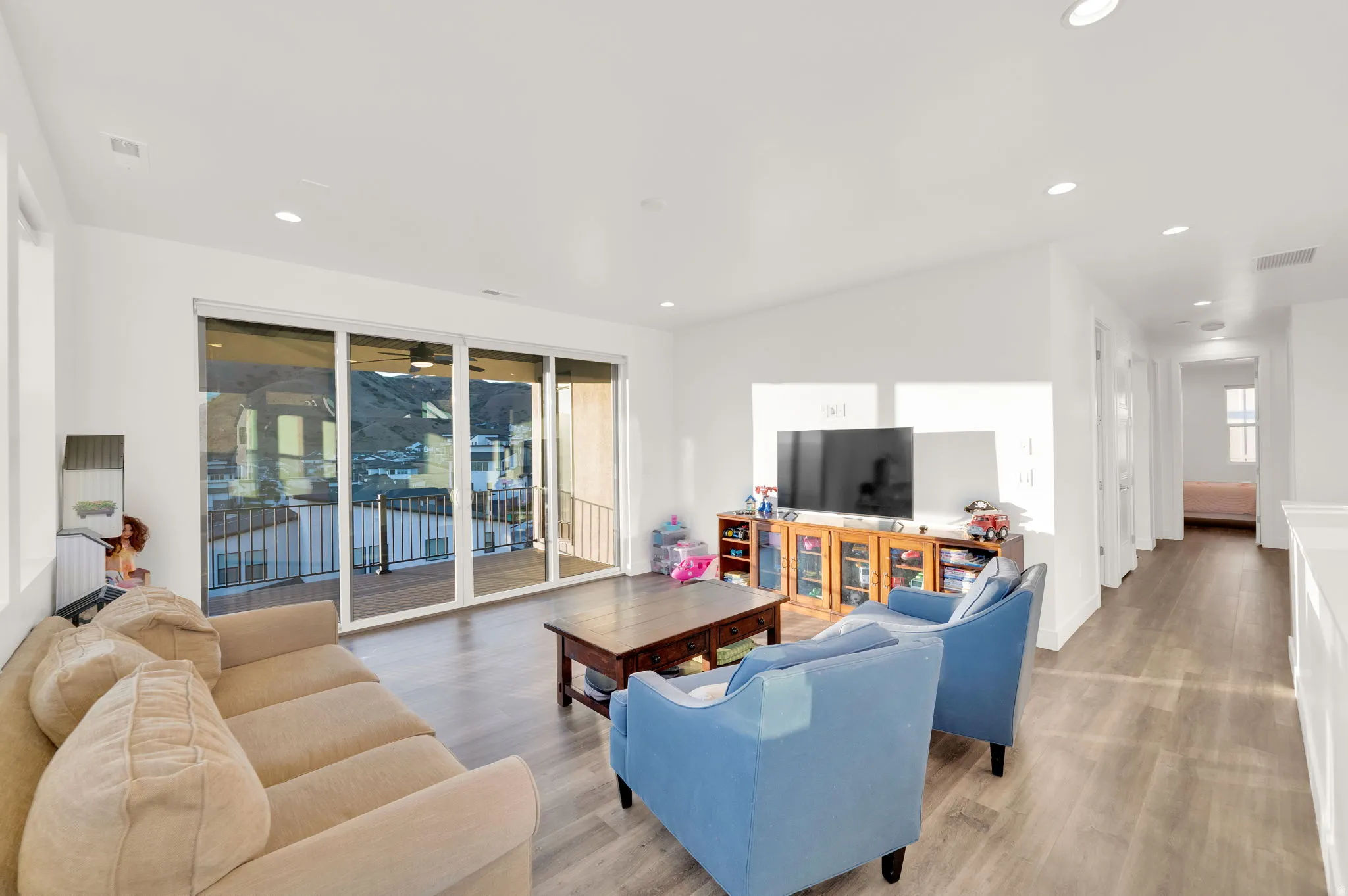 Spacious living area featuring large sliding glass doors opening to an outdoor balcony with a railing