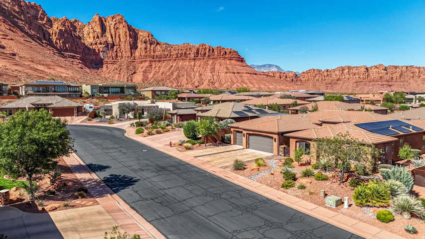 Residential community featuring single-story homes with tile roofs, solar panels, and attached garages