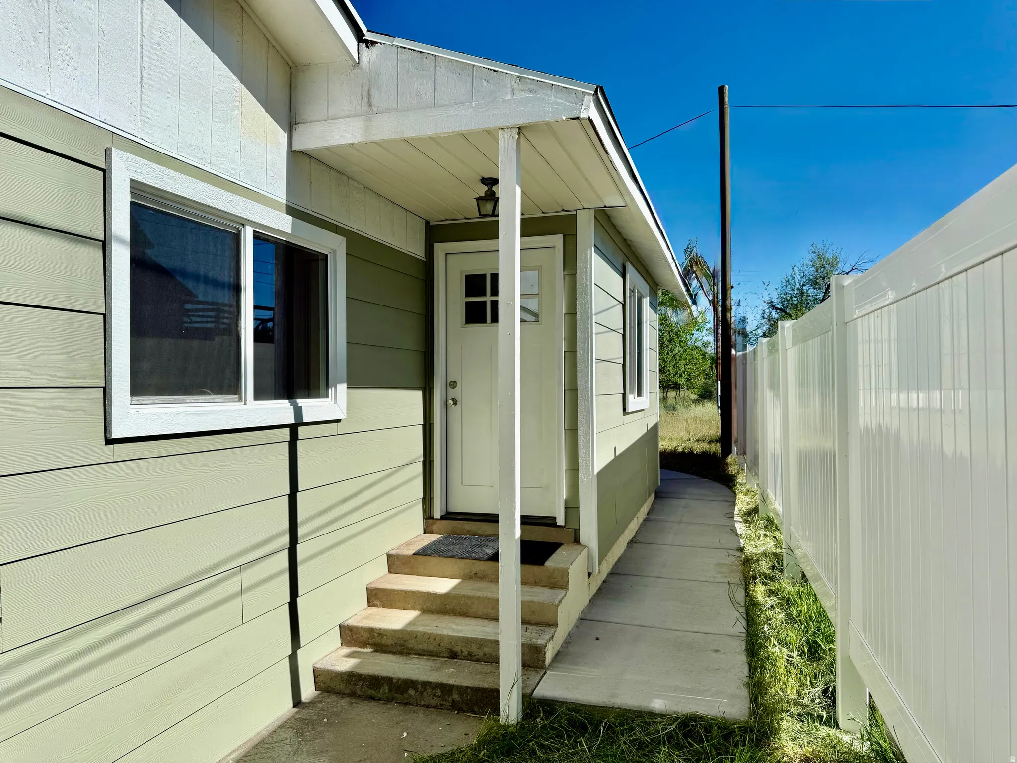 Entryway featuring a covered porch, durable siding, multi-pane door, and concrete steps