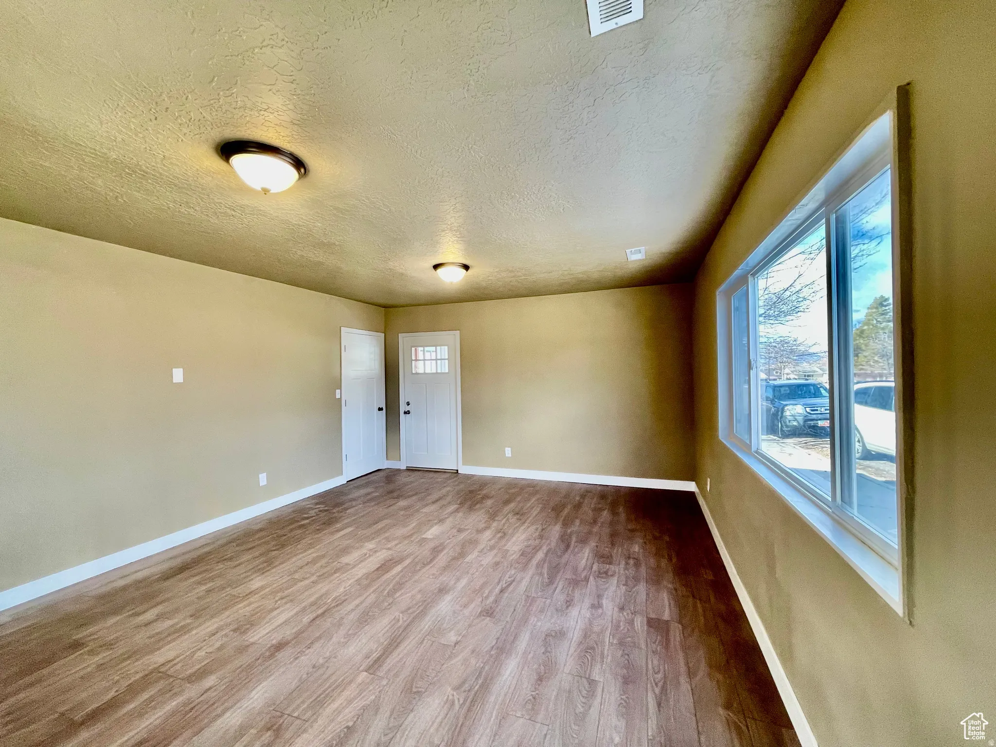 Open interior space featuring wood-finish flooring, neutral-toned walls, and a large window