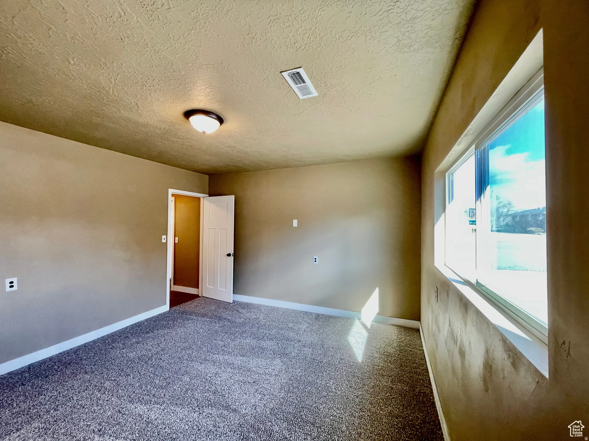 Spacious room featuring new gray carpet, neutral wall paint, and white trim