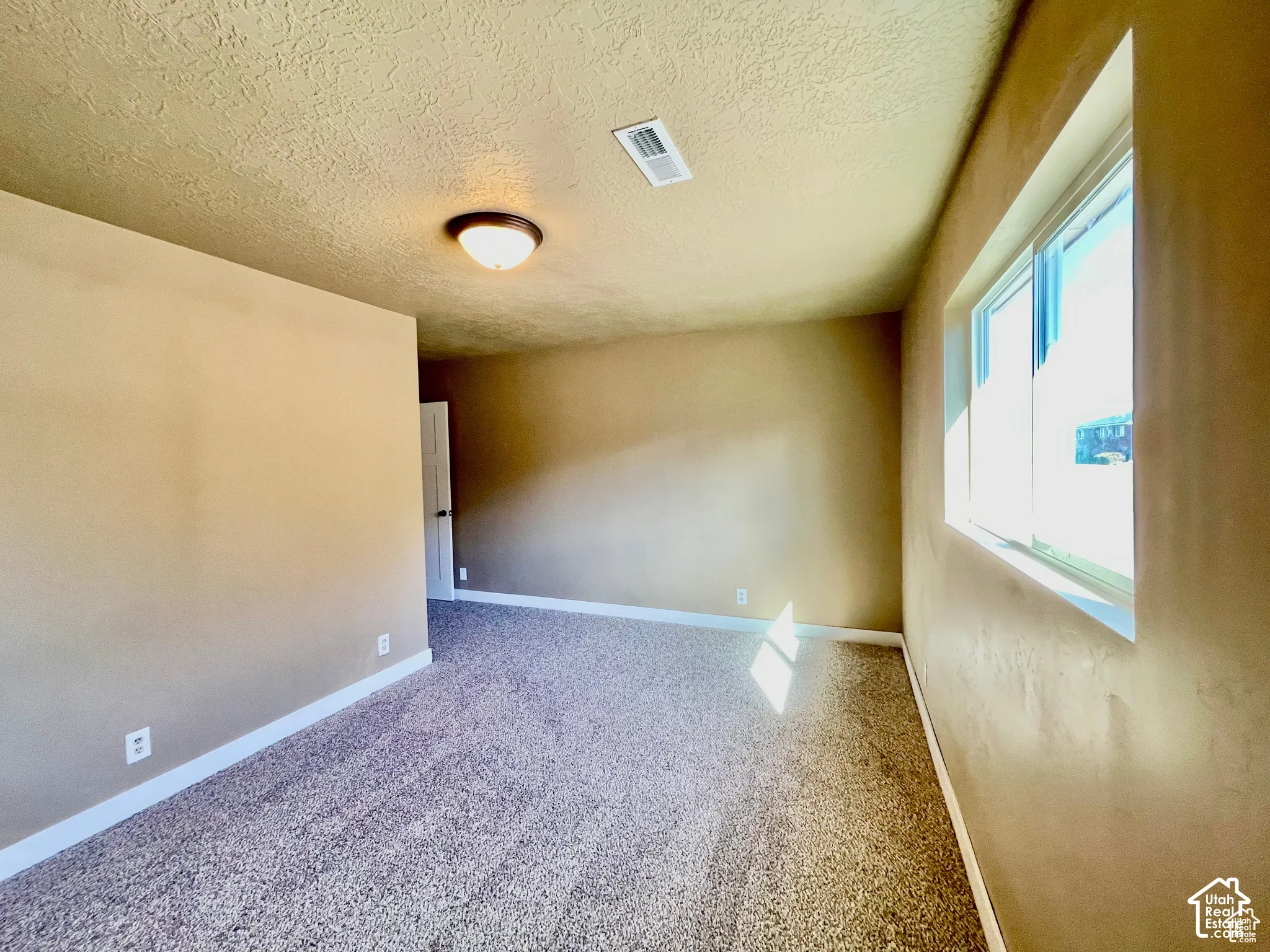 Carpeted interior space with neutral wall tones and a single window