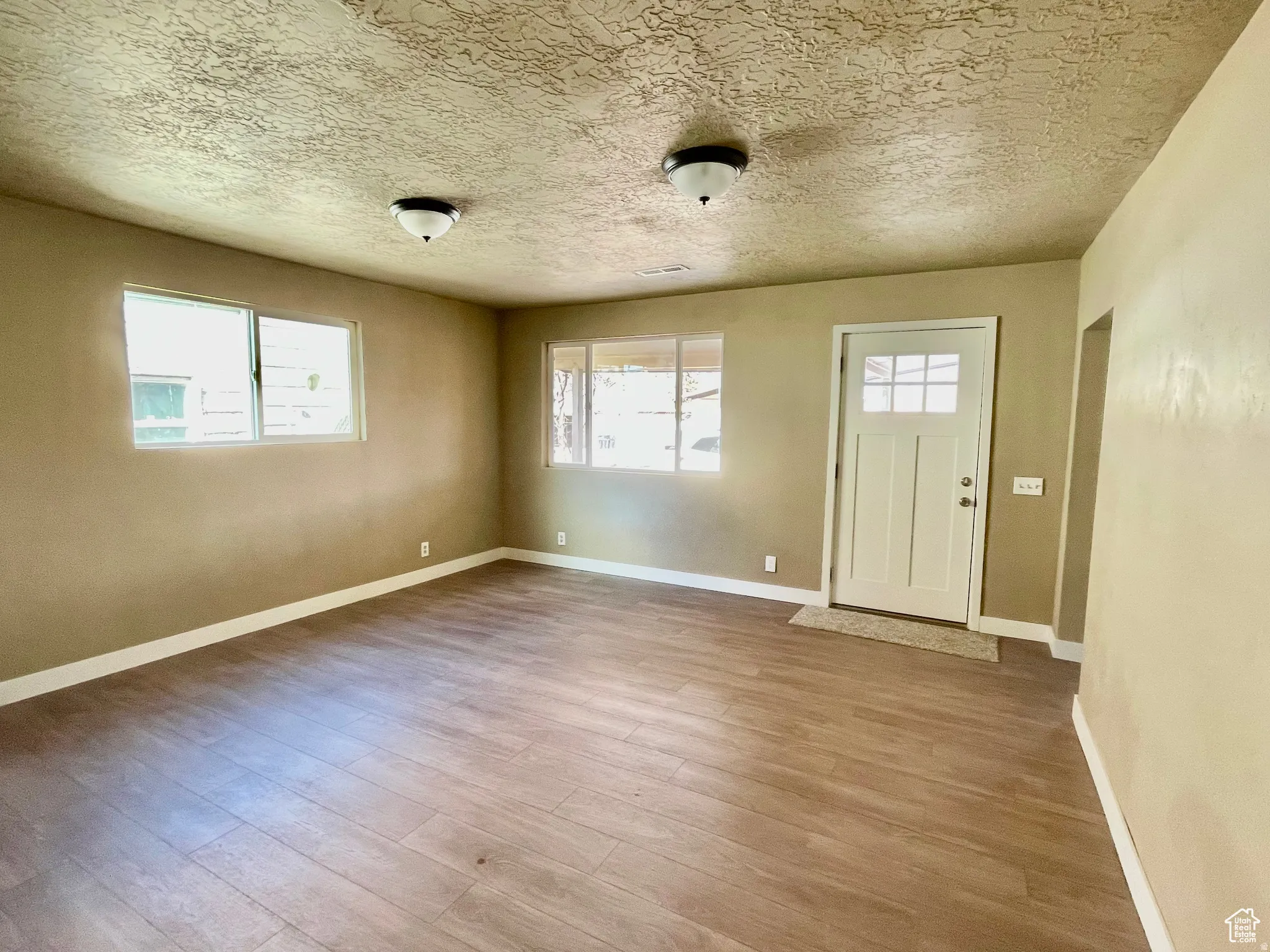 Open concept living space featuring wood-finish flooring and a craftsman-style entry door
