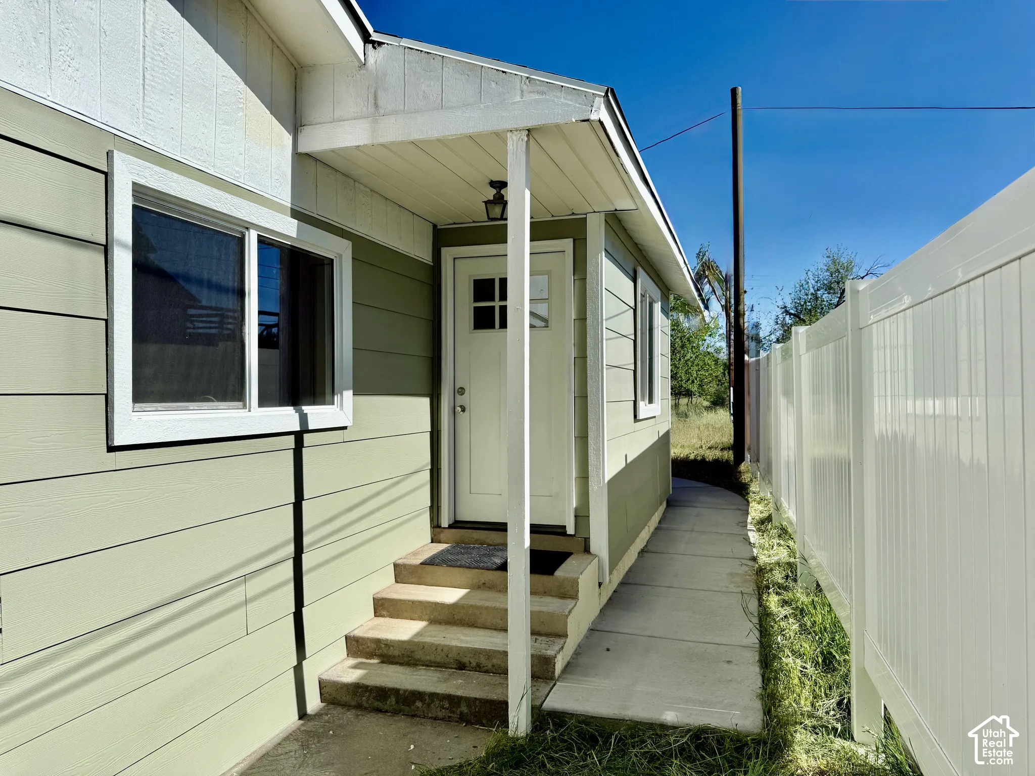 Entryway featuring a covered porch, durable siding, multi-pane door, and concrete steps
