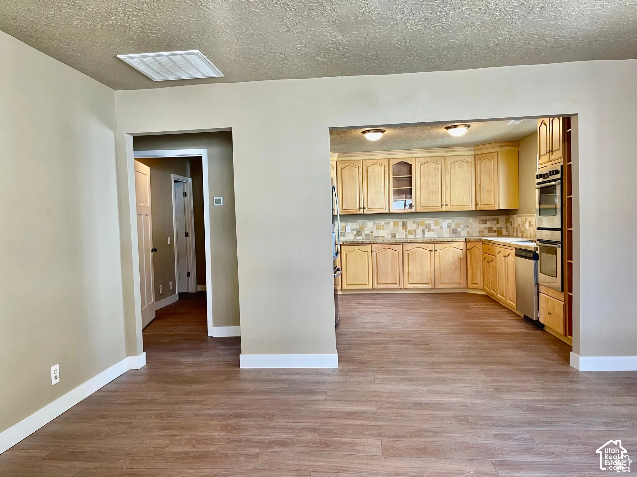 Kitchen featuring light wood cabinetry, a mosaic tile backsplash, stainless steel appliances, and ceiling-mounted lighting