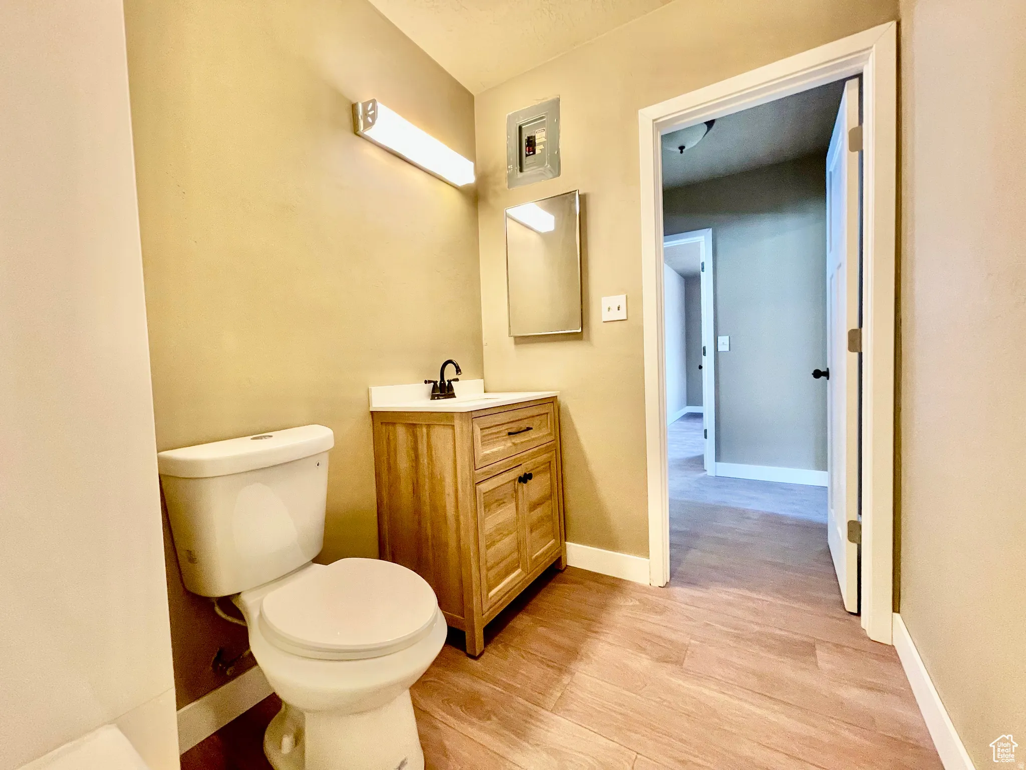 Bathroom with wood-finish flooring, a light wood-tone vanity, and a white countertop