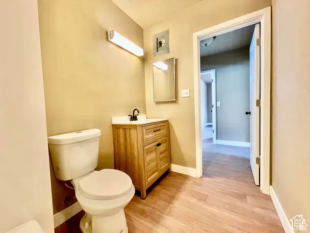 Bathroom with wood-finish flooring, a light wood-tone vanity, and a white countertop