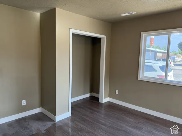 Spacious interior room featuring wood-finish flooring, neutral wall paint, and white trim