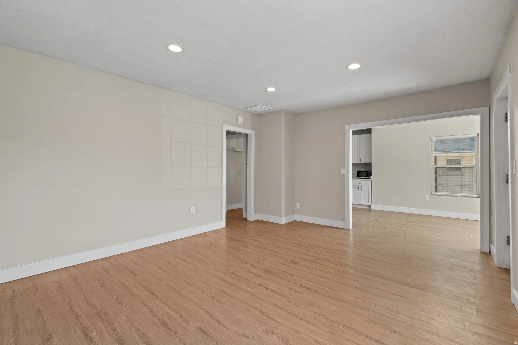 Spacious interior room featuring wood-finish flooring and recessed lighting