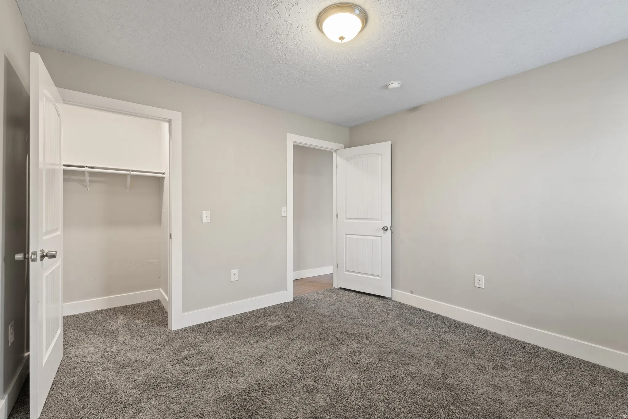 Interior room featuring plush gray carpeting, light neutral wall paint, and white trim