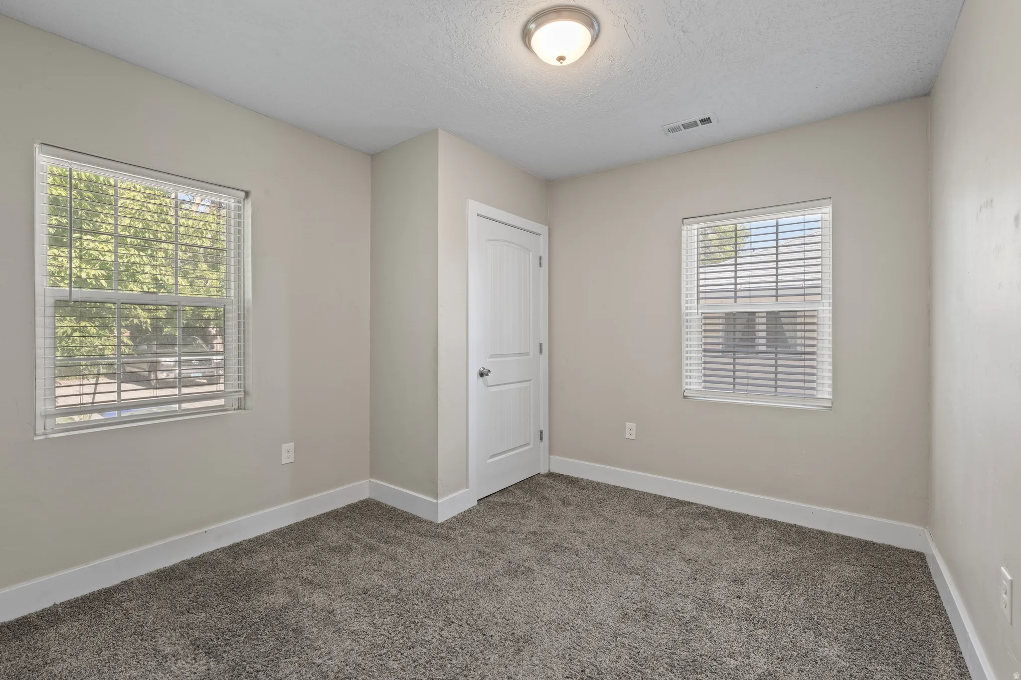Carpeted room with neutral wall tones and white baseboards