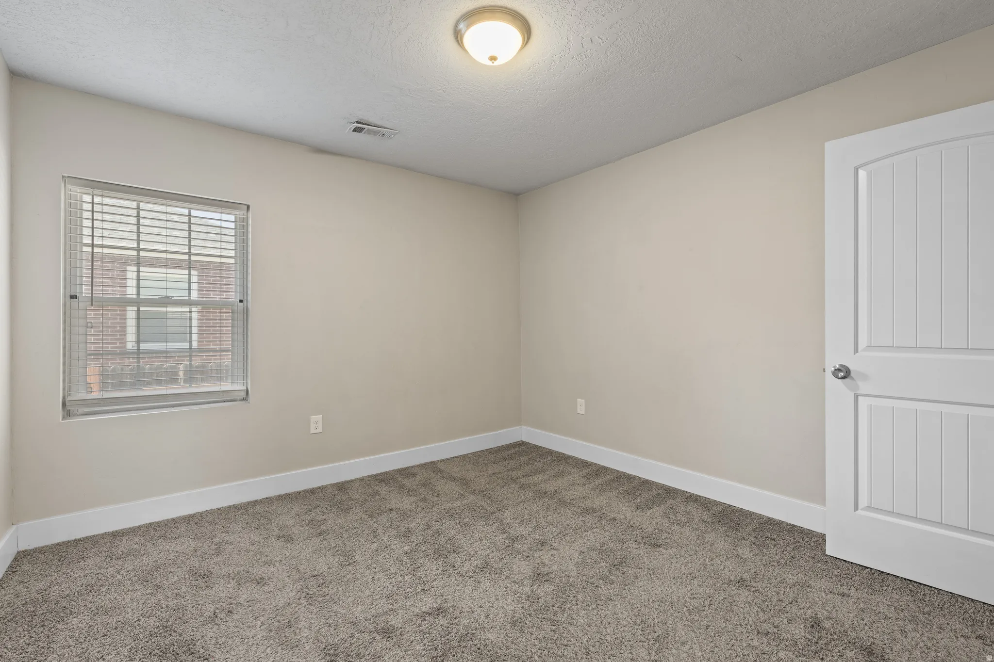 Neutral tone walls featuring white trim, complementing the plush gray carpet