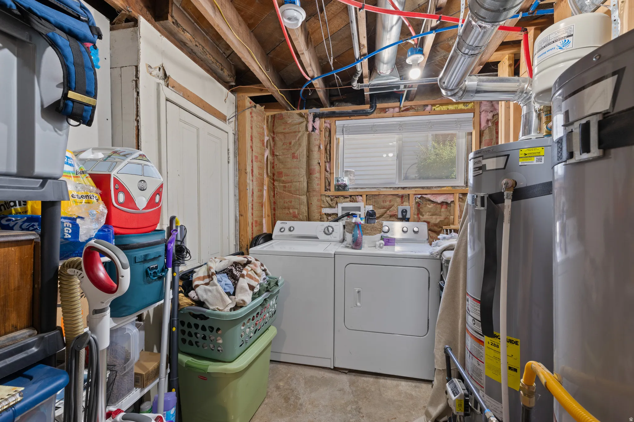 Dedicated laundry area featuring a washer and dryer, exposed ceiling joists, and a window with blinds