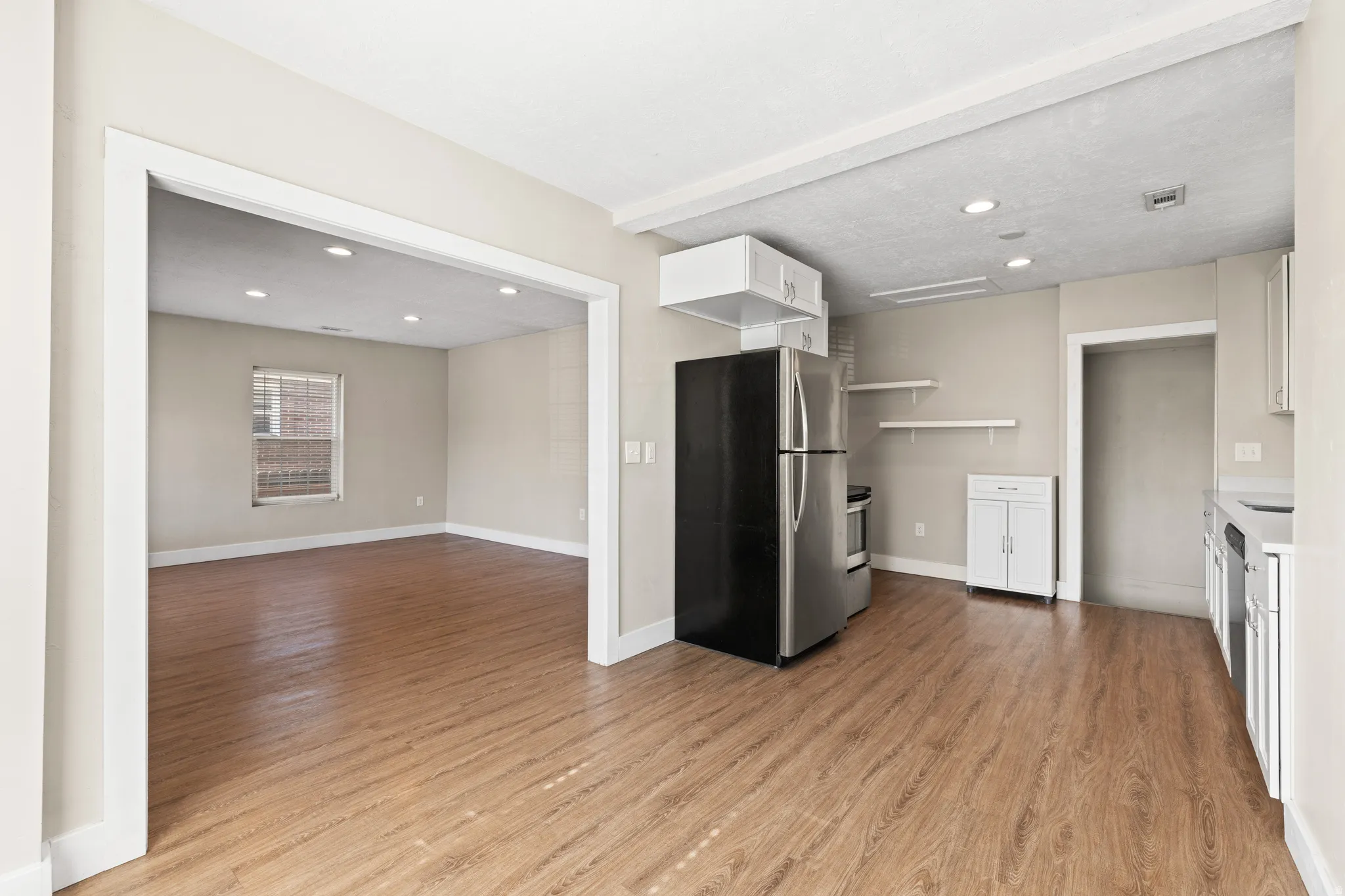Open-concept kitchen area featuring wood-finish flooring, recessed lighting, and white cabinetry