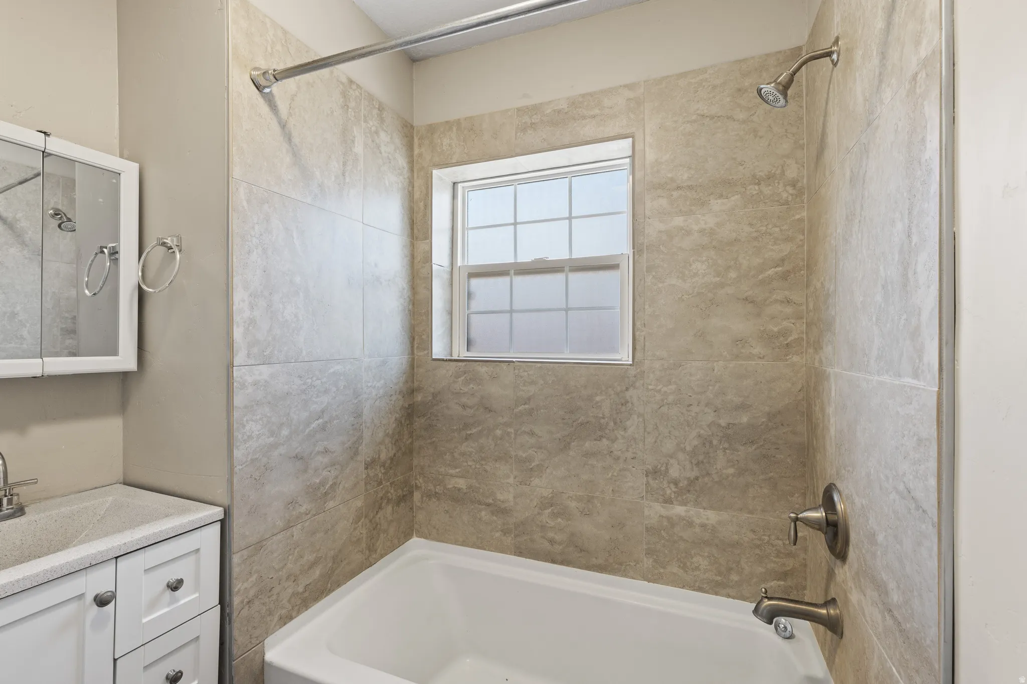 Bathroom featuring a white tub, shower with bronze fixtures, and light-colored tile surround