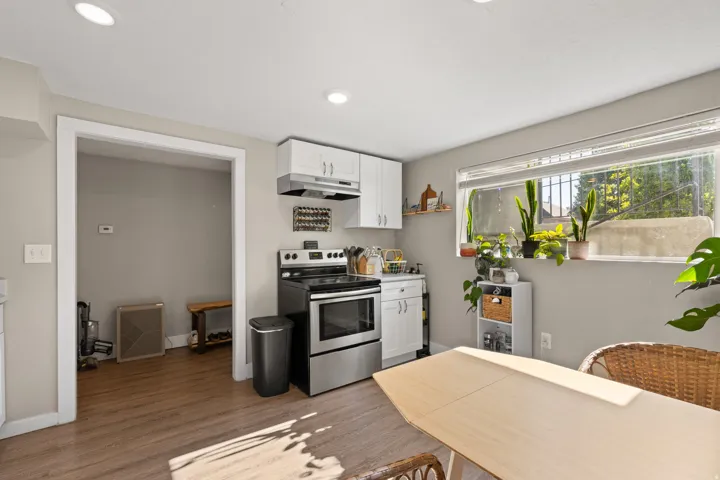 Compact kitchen featuring white cabinetry, stainless steel range, and wood-finish flooring