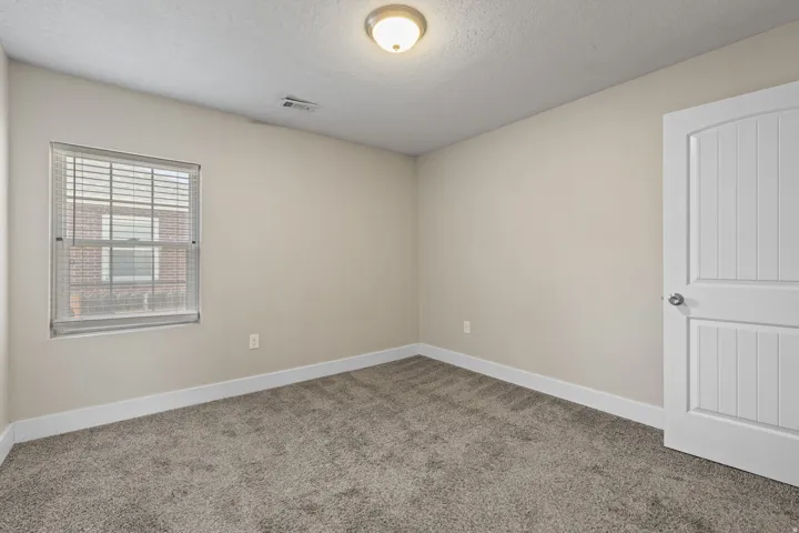 Neutral tone walls featuring white trim, complementing the plush gray carpet