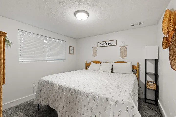 Carpeted bedroom with a window featuring horizontal blinds, recessed lighting, and a white ceiling