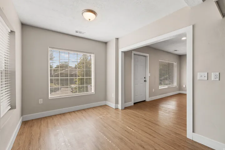 Bright interior space featuring wood-finish flooring, neutral paint tones, multiple windows, and a recessed ceiling light fixture