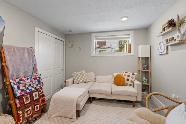 Carpeted room with light gray walls, featuring a window with white trim, built-in shelving, and white bi-fold closet doors