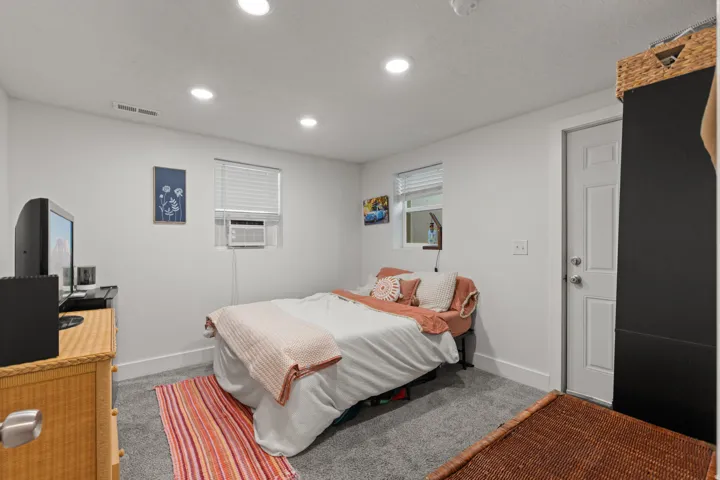 Room featuring recessed lighting, a white painted door, gray carpeting, a window with blinds, and a wall-mounted air conditioning unit