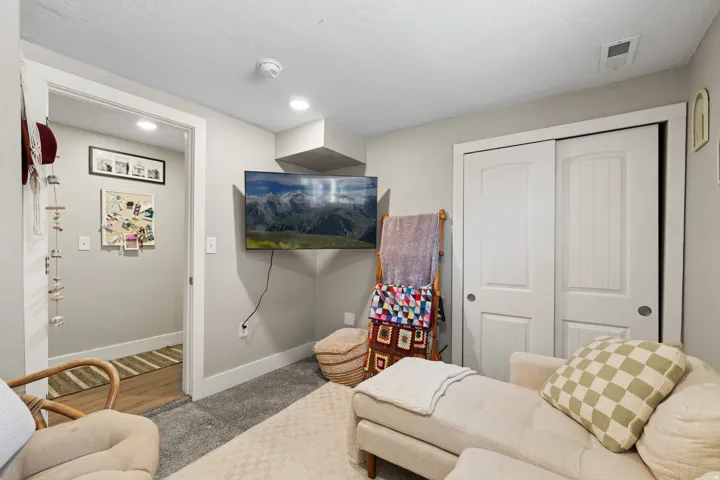 Carpeted interior space featuring a mounted television and white bi-fold closet doors