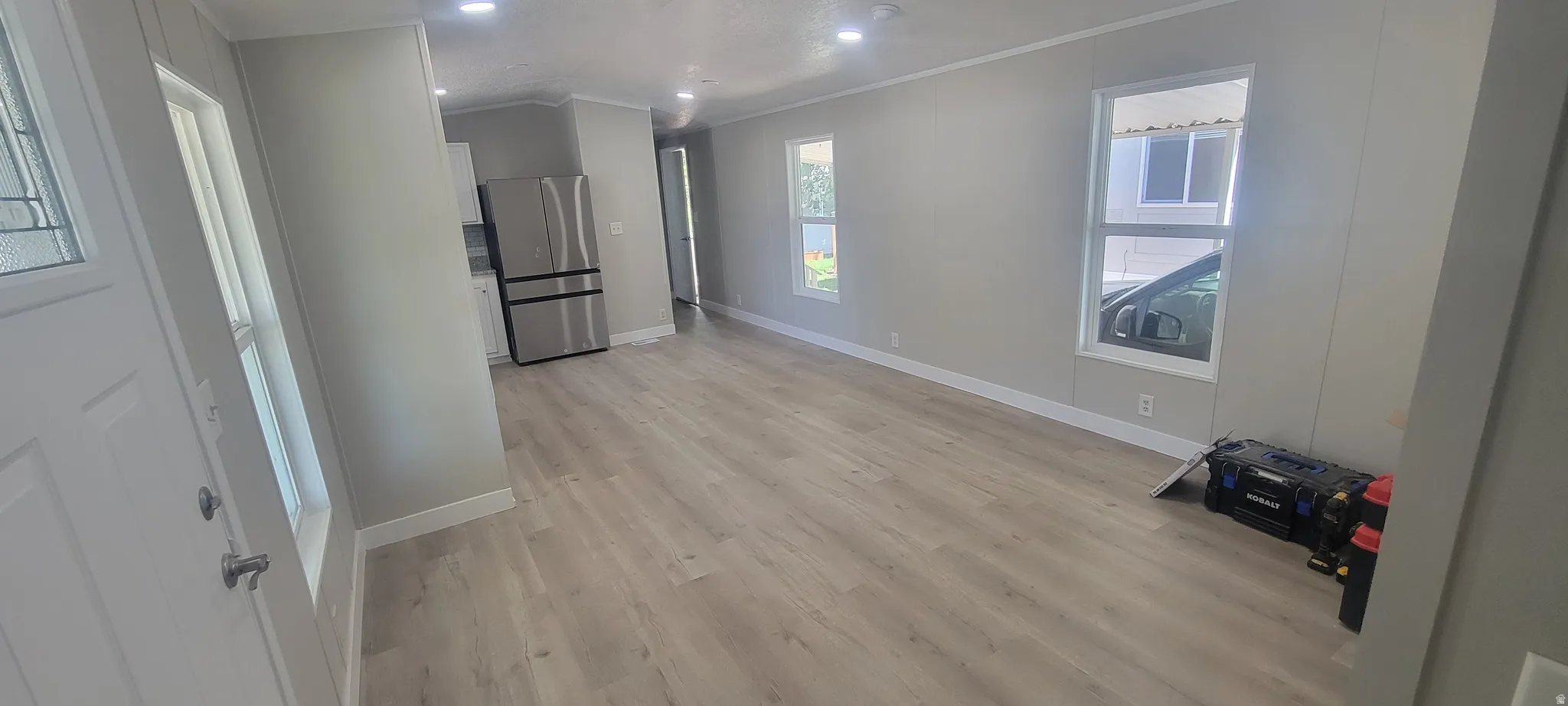 Expansive open-concept living area featuring light wood-finish flooring, recessed ceiling lighting, and multiple windows