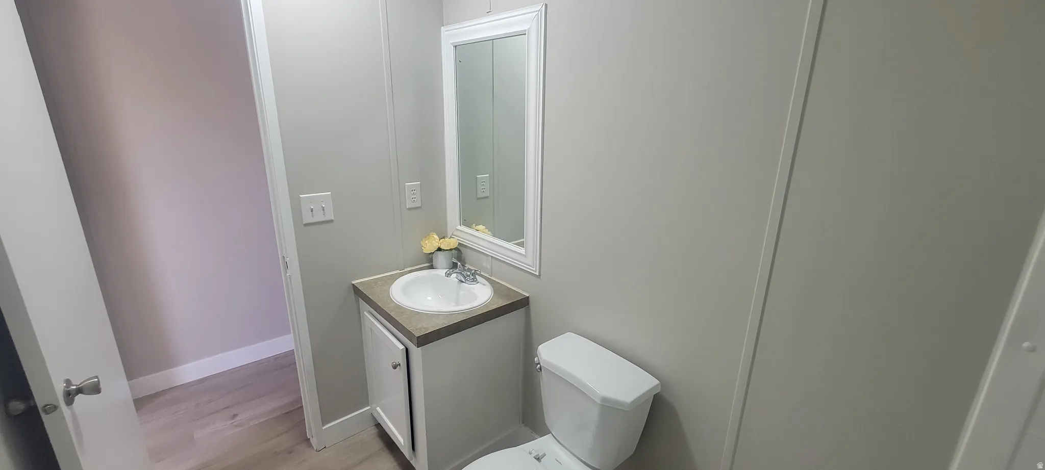 Bathroom featuring a white vanity cabinet with a light-colored countertop, an undermount sink, and a framed wall mirror