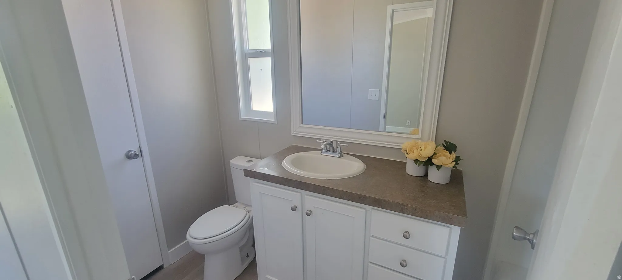 Bathroom featuring a white vanity with built-in storage, an integrated sink, and a framed mirror
