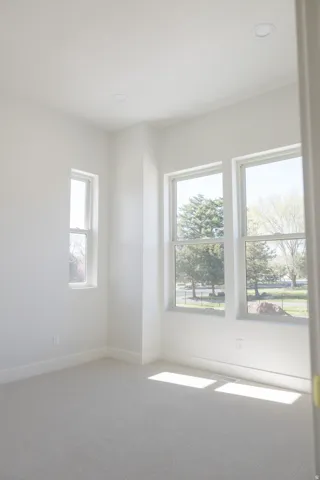 Bright interior room featuring light-toned walls, recessed ceiling lighting, and a light-colored carpeted floor