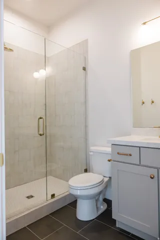 Bathroom featuring a glass-enclosed shower with light-toned rectangular wall tiles and a white hexagonal tile floor