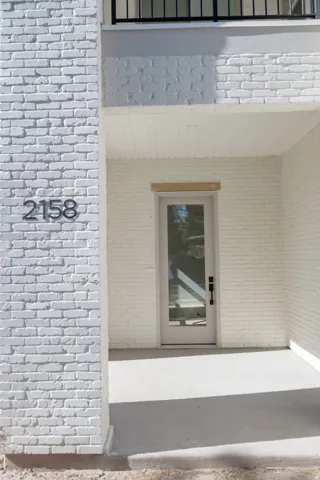 White-painted brick exterior featuring a glass-paneled entry door with a black hardware finish