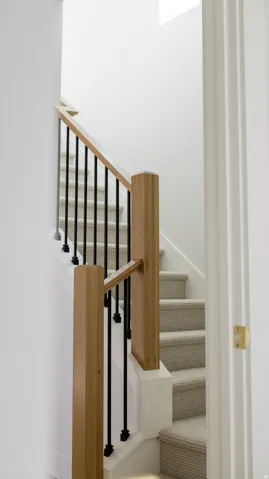 Carpeted staircase with white risers and modern wood newel posts