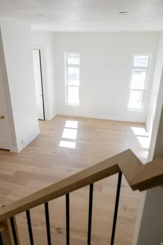 Open-concept room featuring light wood-finish flooring, white walls, and two vertical windows