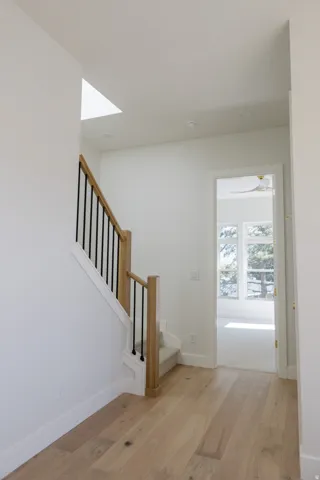 Entryway featuring light wood-finish flooring, a contemporary staircase with wood newel posts and black metal balusters, and recessed ceiling lighting